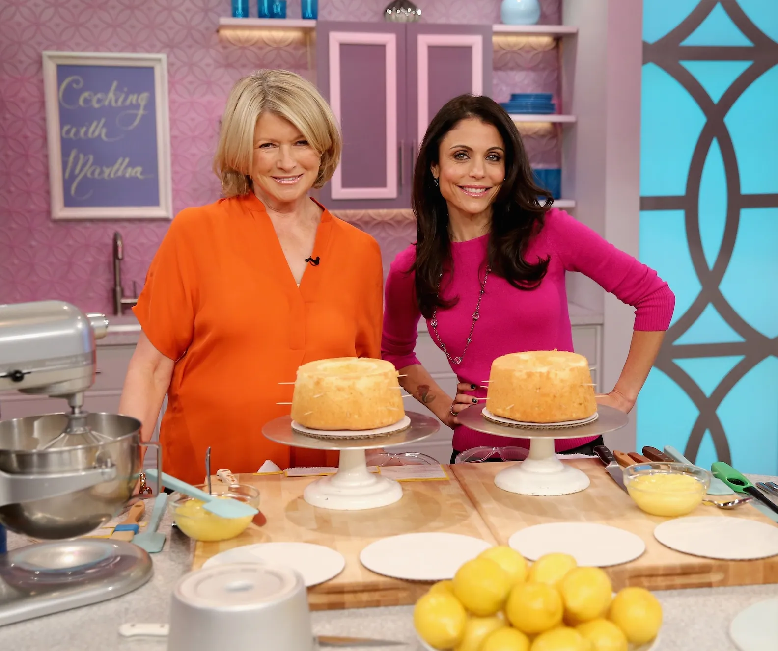 Bethenny Frankel and Martha Stewart posing together in front of a counter with two cakes for a show in 2013