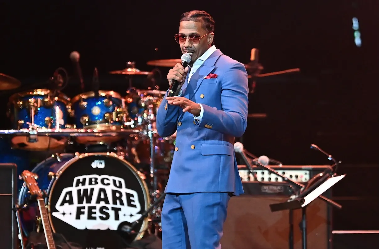 Nick Cannon speaks onstage during the 2026 HBCU AWARE FEST. He's wearing a blue suit and standing in front of a drum set.