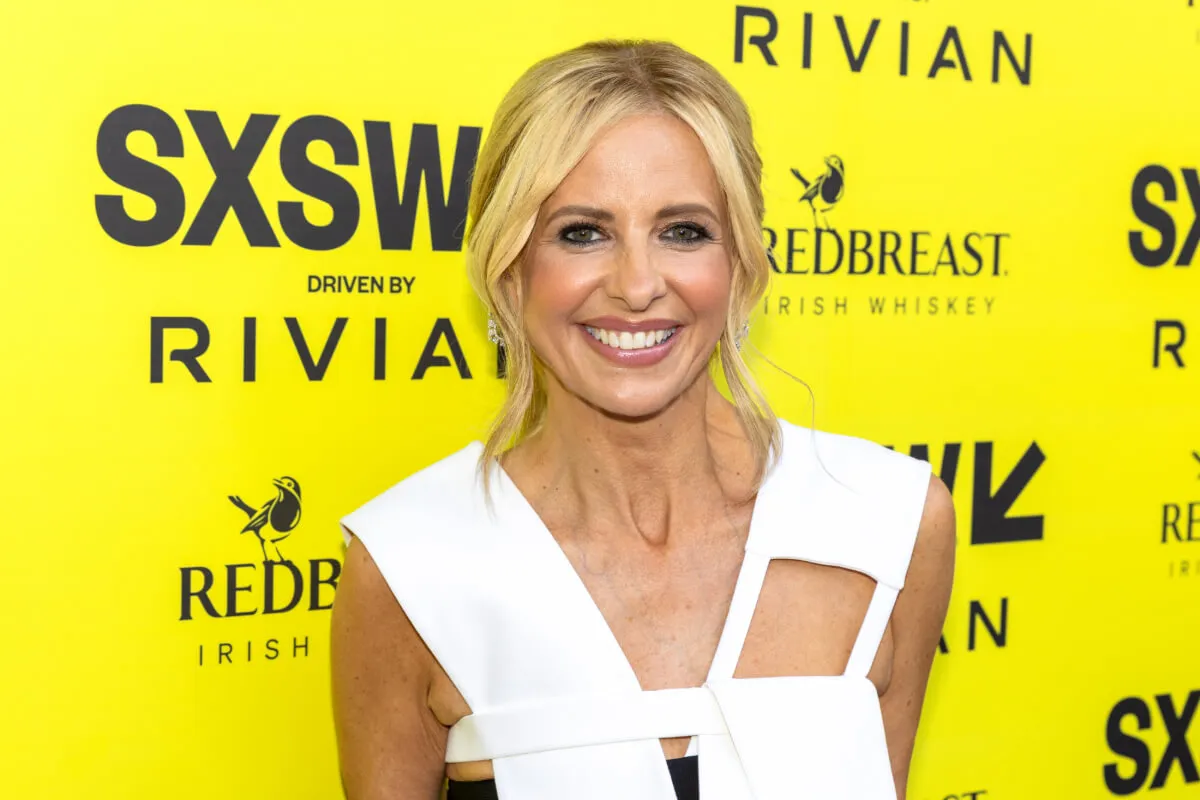 Sarah Michelle Gellar wears a white dress and stands in front of a yellow background.