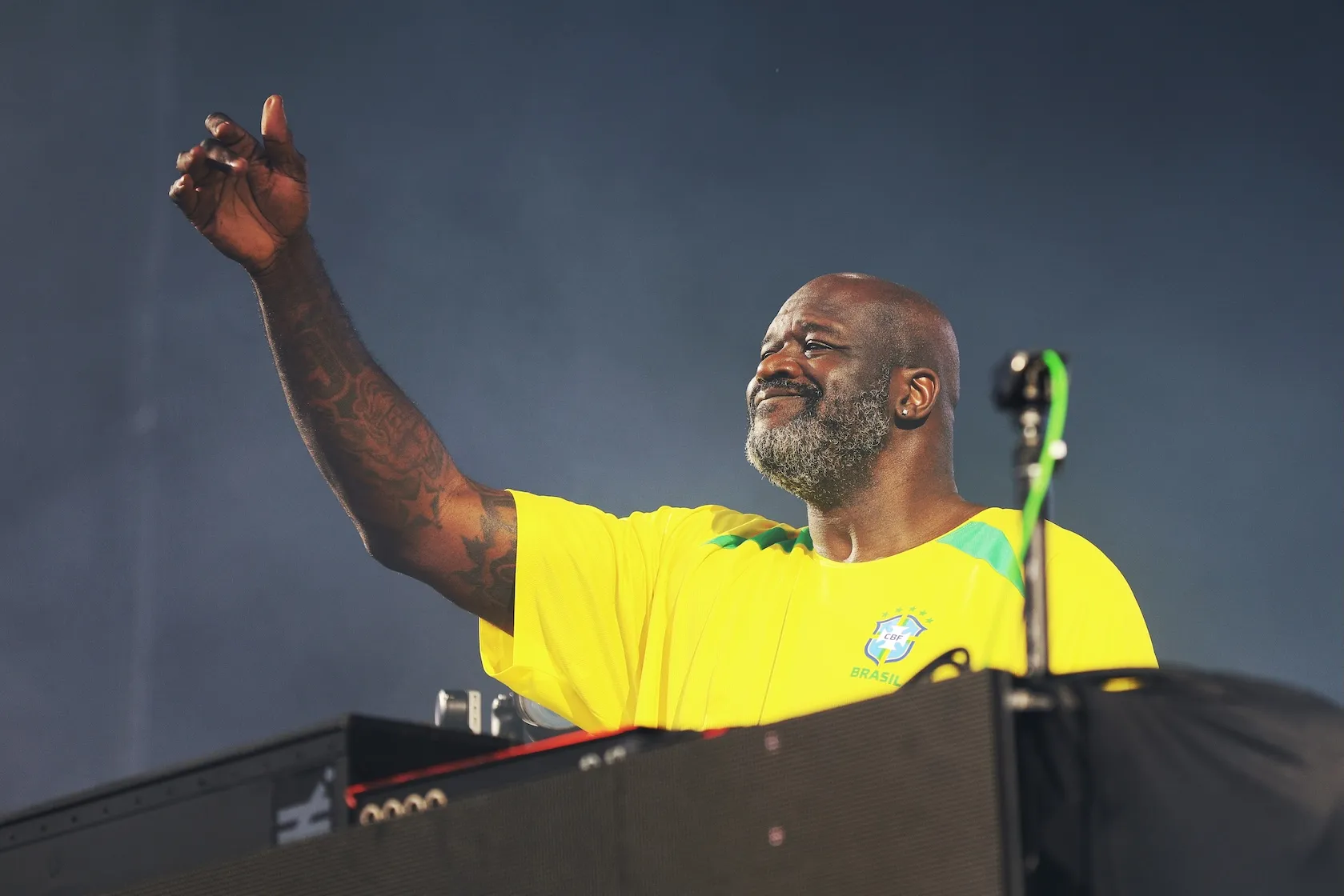 DJ Diesel aka Shaquille O'Neal playing his music on a stage while wearing a yellow T-shirt.
