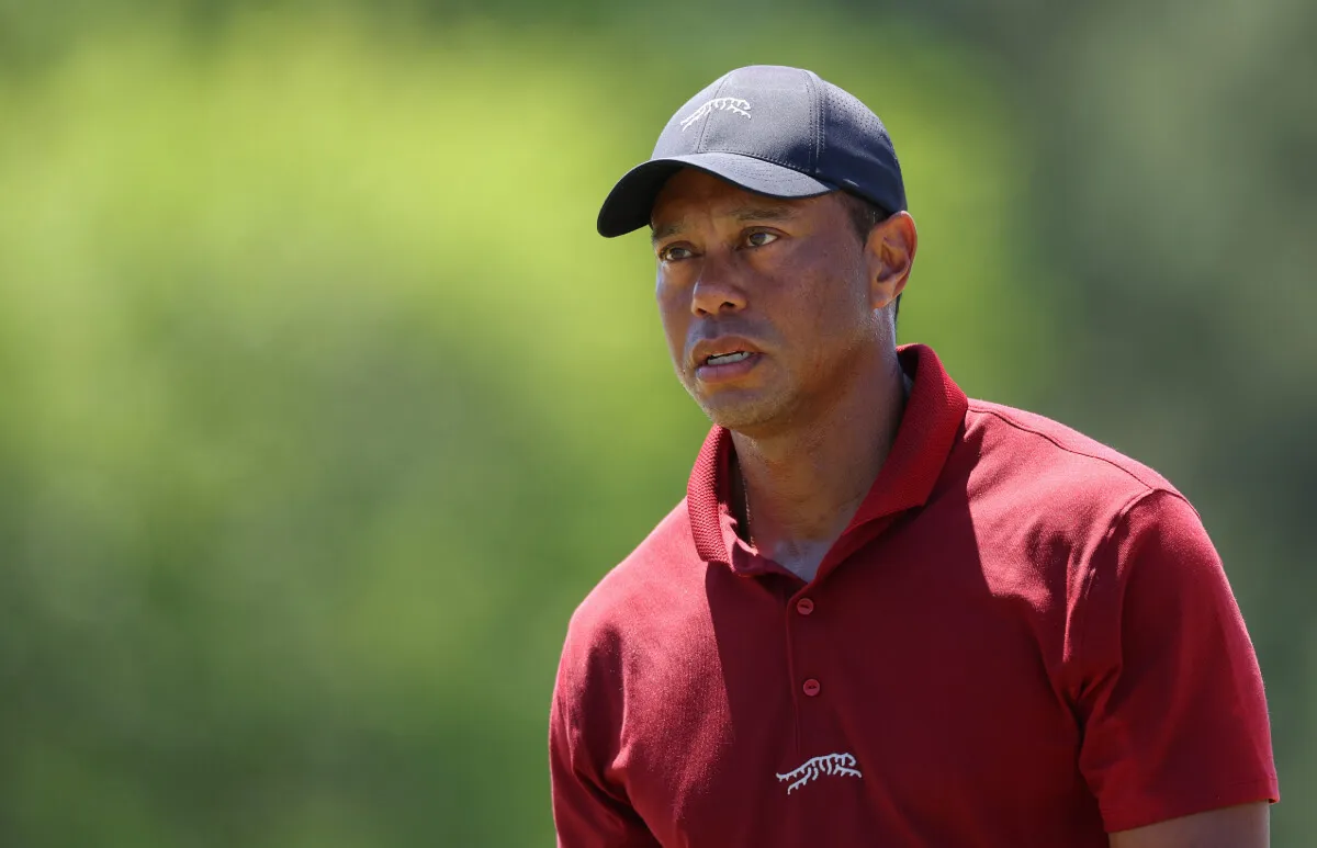 Tiger Woods wears a red polo and a blue baseball hat.