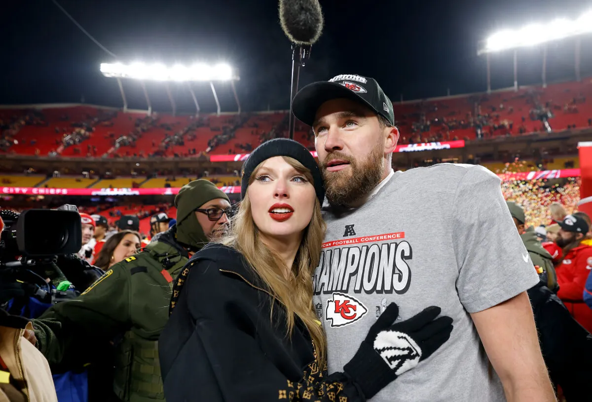 Taylor Swift wears black and embraces Travis Kelce on the football field.