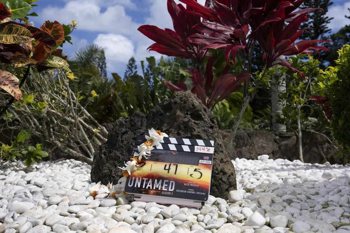 A clapperboard for Untamed Season 2 sitting on the beach in Hawai'i