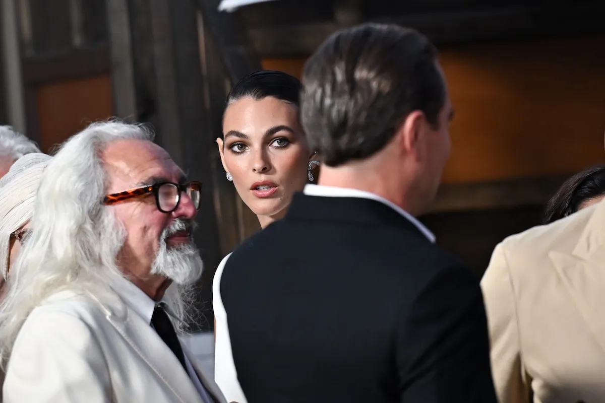 Vittoria Ceretti looking toward the camera while Leonardo DiCaprio is facing the other way beside her. They're at the 'One Battle After Another' premiere in 2025