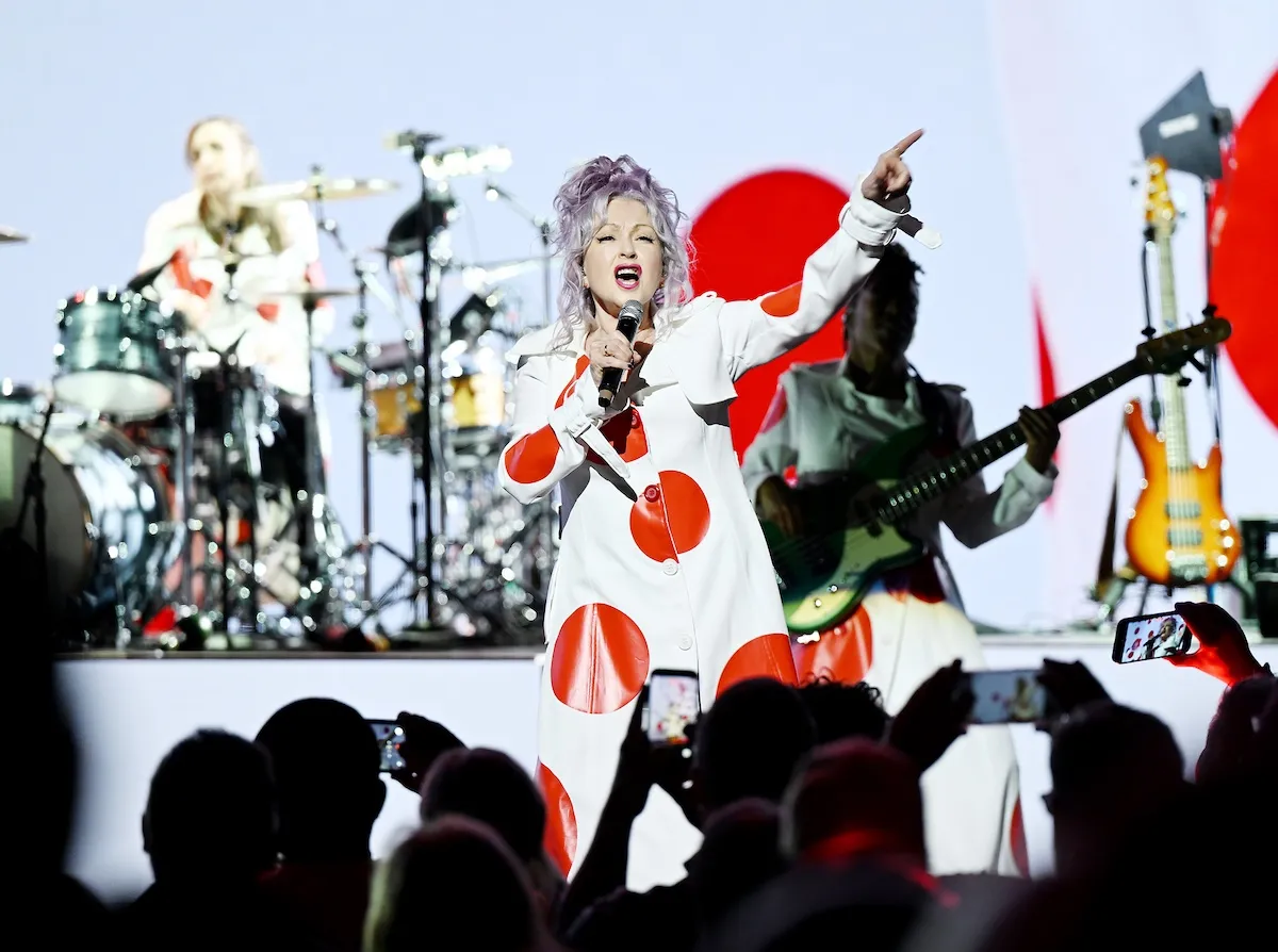 Cyndi Lauper wearing an outfit with red polka dots on stage in Las Vegas