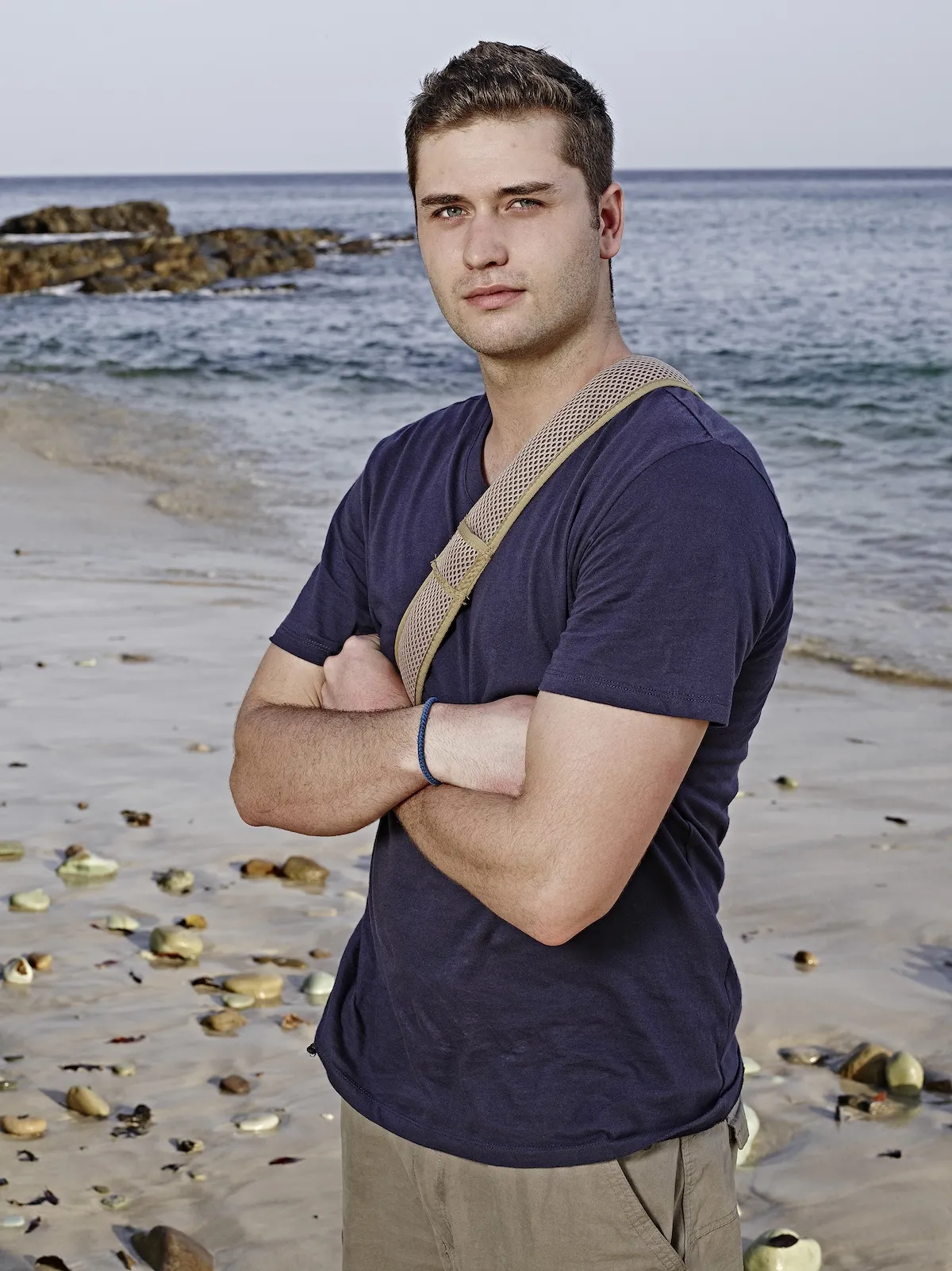 Dakota Mortensen standing on a beach in a promo shot for 'The Island'