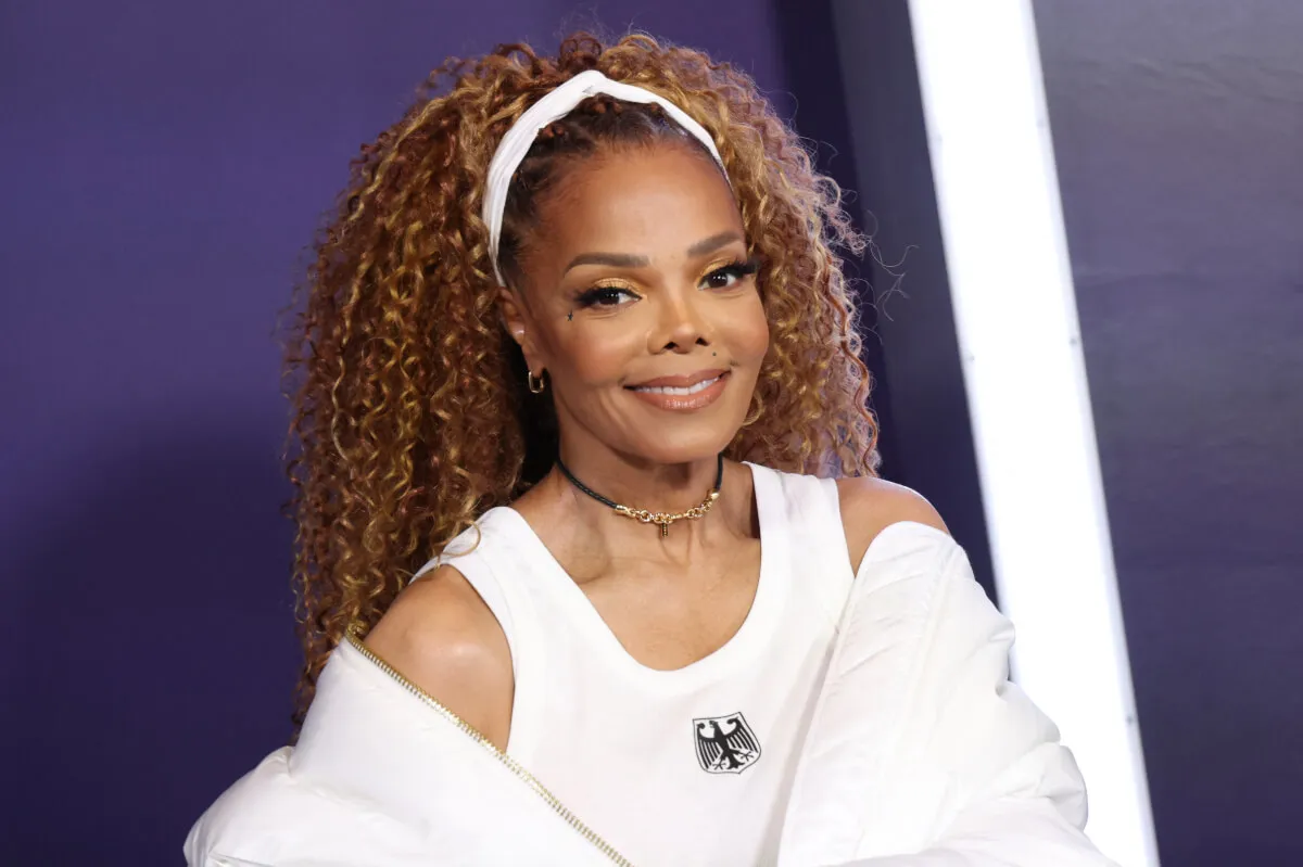 Janet Jackson wears a white tank top, jacket, and headband.
