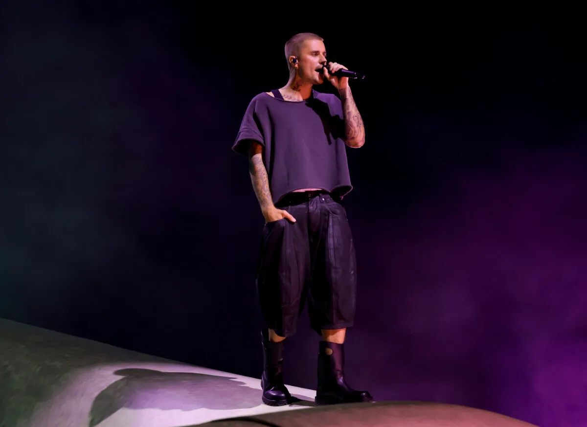 Justin Bieber wears a black shirt and shorts and sings into a microphone at Coachella.