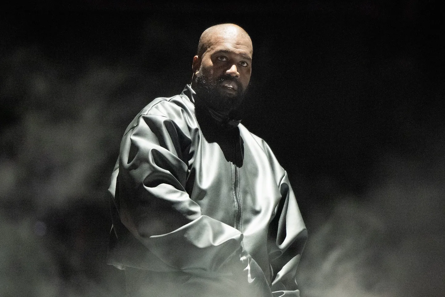 Kanye West performs onstage in 2024 against a black background