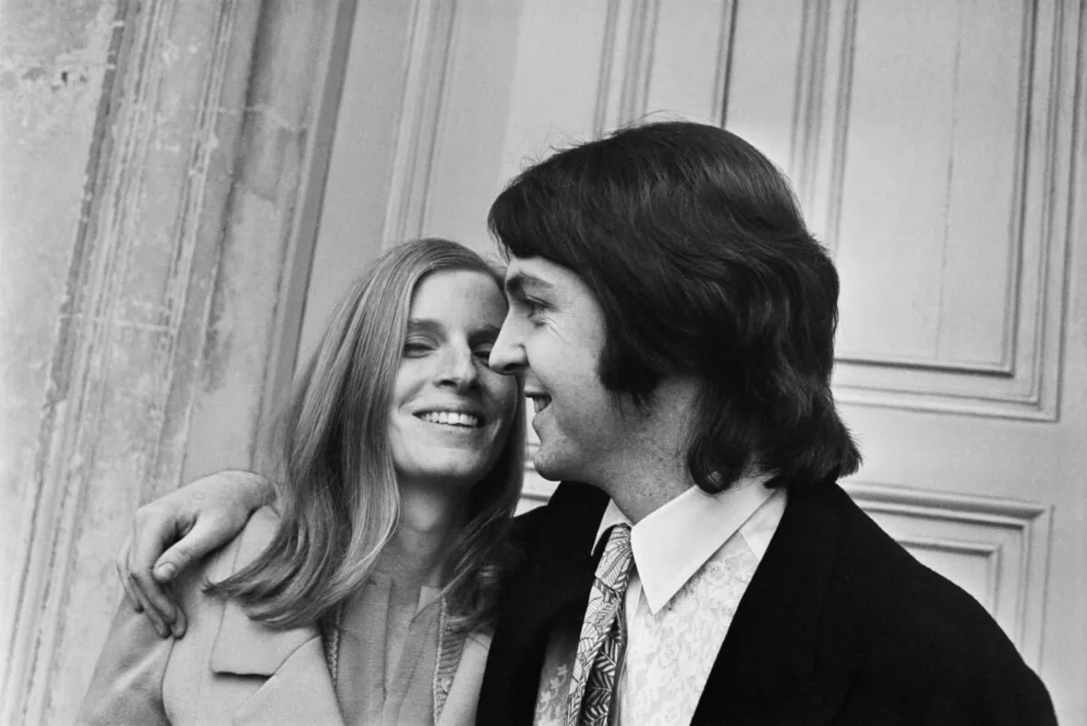 A black and white picture of Paul McCartney standing with his arm around Linda McCartney.