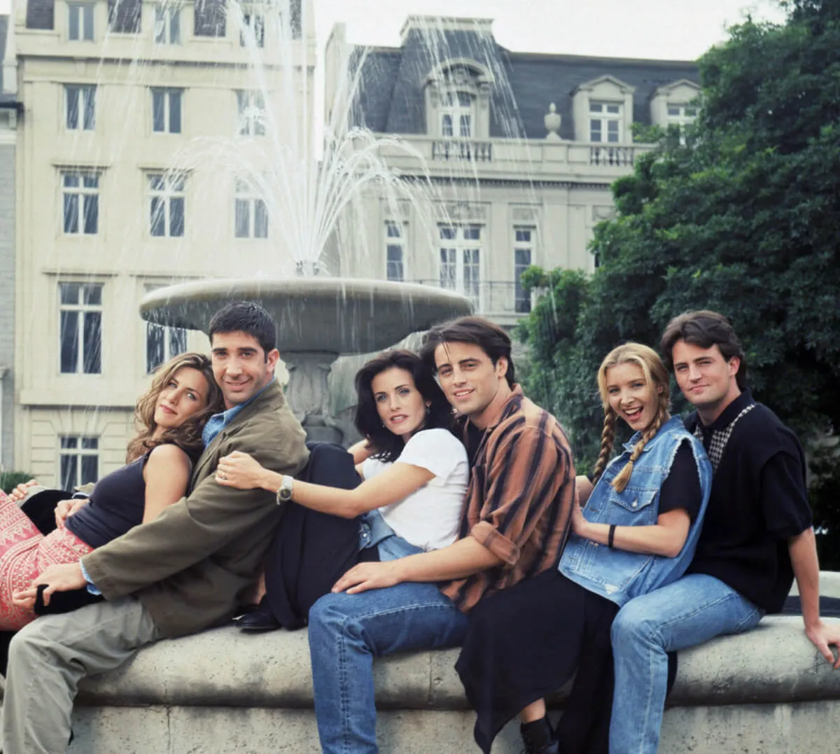 The cast of friends --Jennifer Aniston, David Schwimmer, Courtney Cox, Matt LeBlanc, Lisa Kudrow, and Matthew Perry -- pose on a fountain together.
