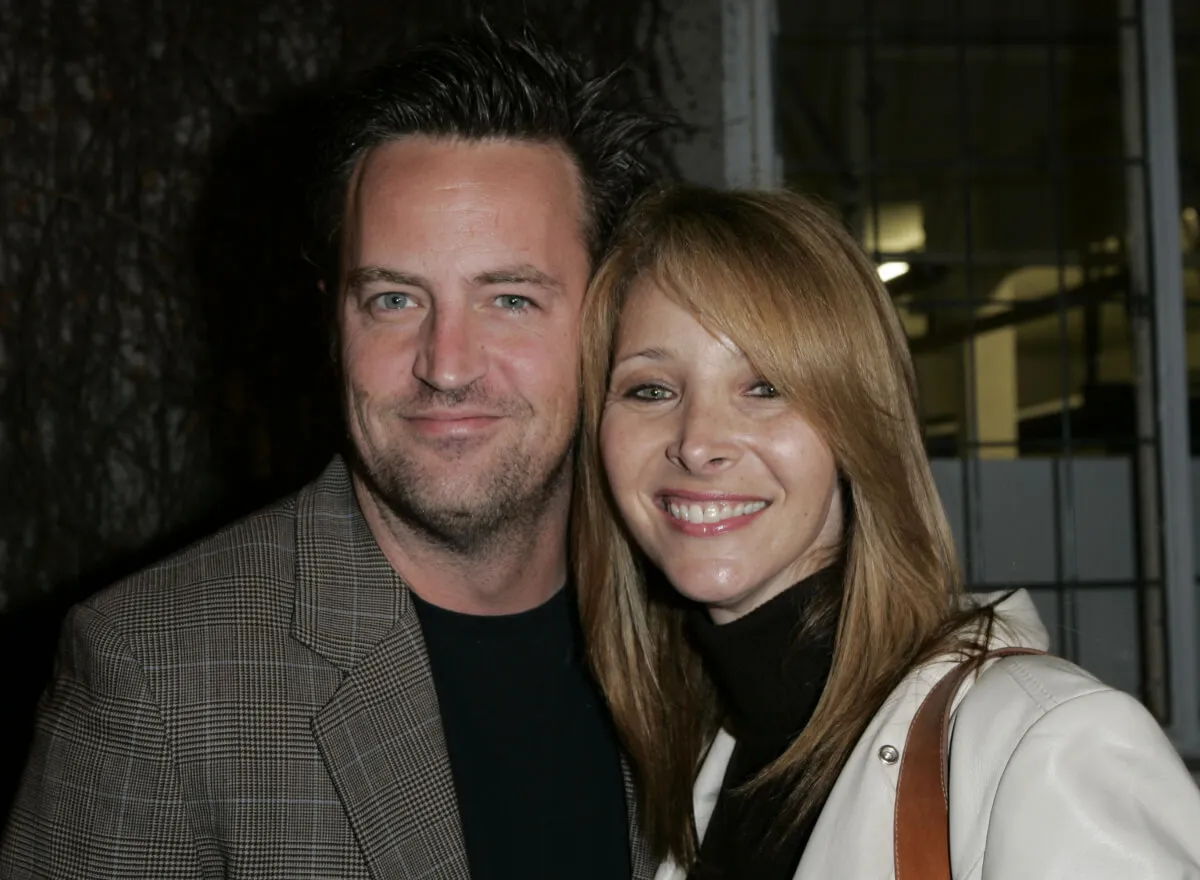 Matthew Perry wears a plaid blazer and poses with Lisa Kudrow, who wears a white leather jacket.