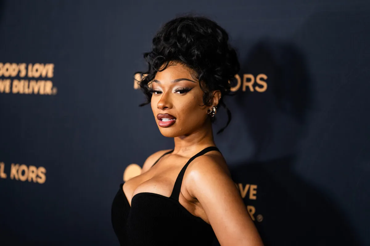 Megan Thee Stallion wears a black dress and has her hair up.