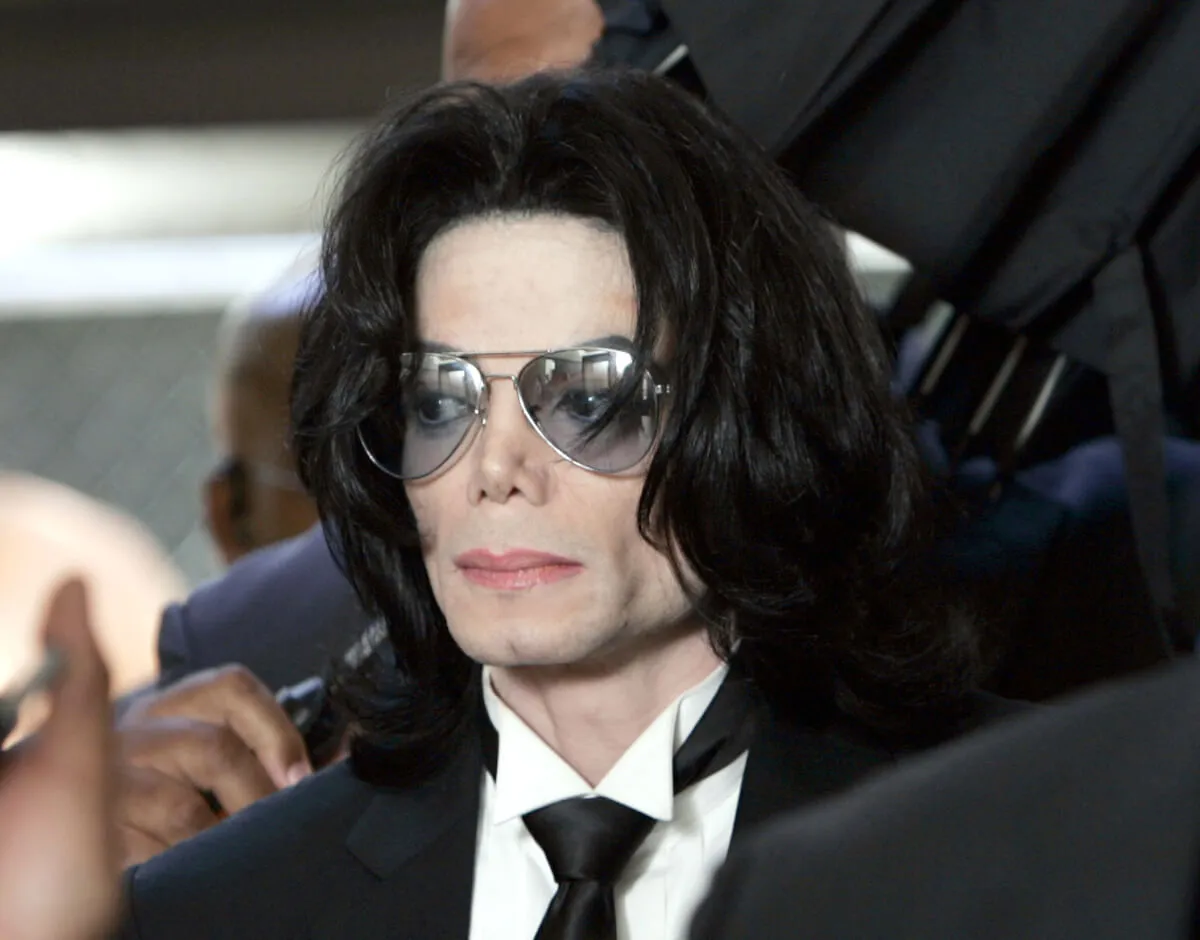 Michael Jackson wears a suit and tinted glasses.