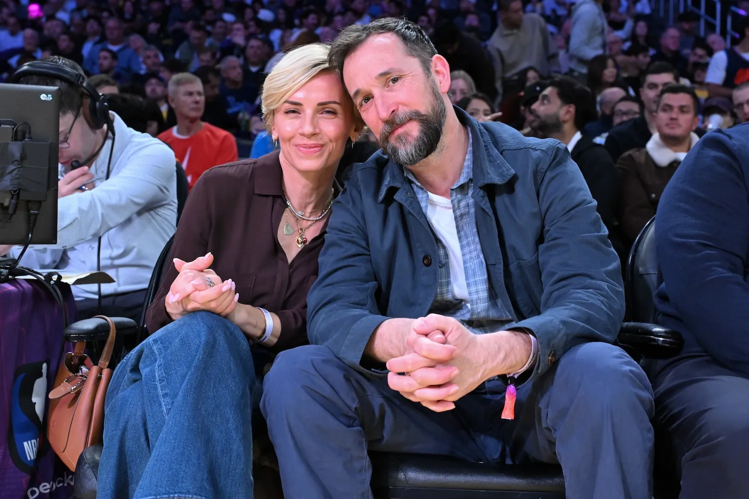 Noah Wyle (R) and Sara Wells posing with their heads touching at a basketball game in February 2026