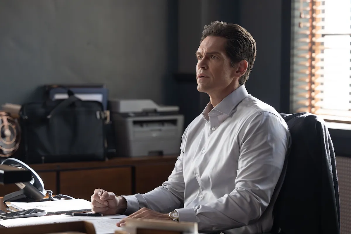 Steve Howey, as Wagner, sitting behind a desk in 'High Potential' Season 2