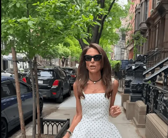 Bethany Frankel wears a white dress with polka dots and black sunglasses.