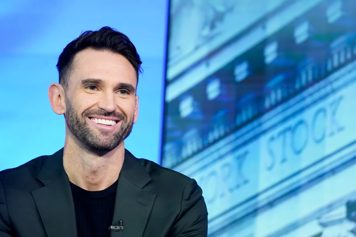 Carl Radke wears black and smiles in front of a blue background.