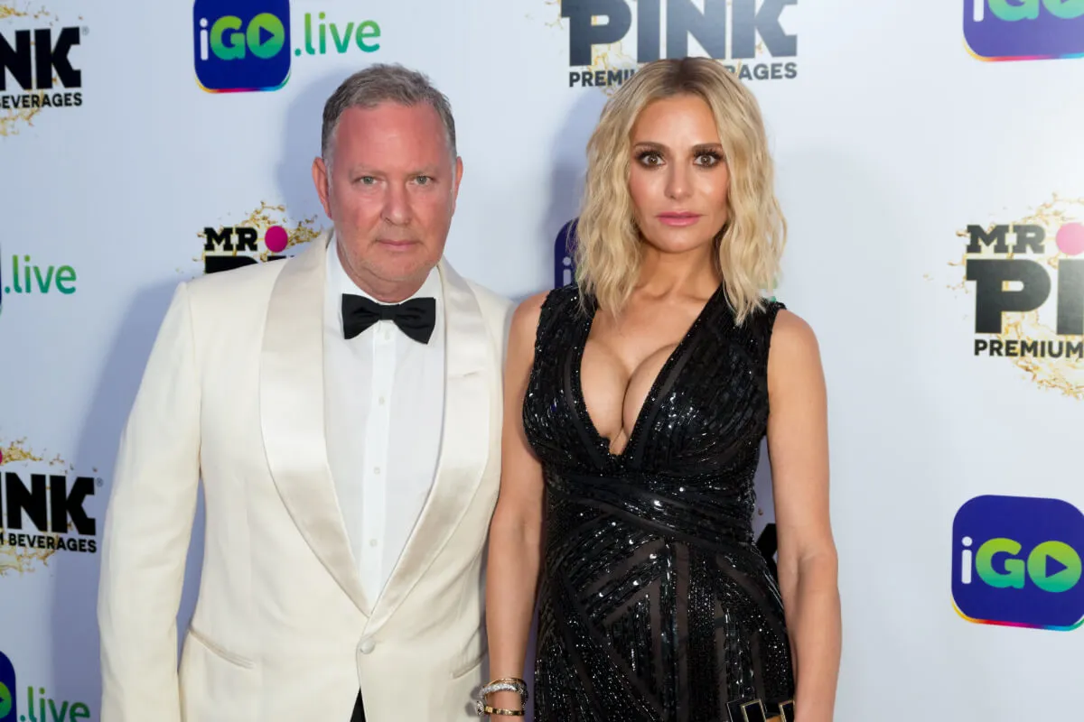 PK Kemsley wears a white tuxedo and stands with Dorit Kemsley, who wears black.