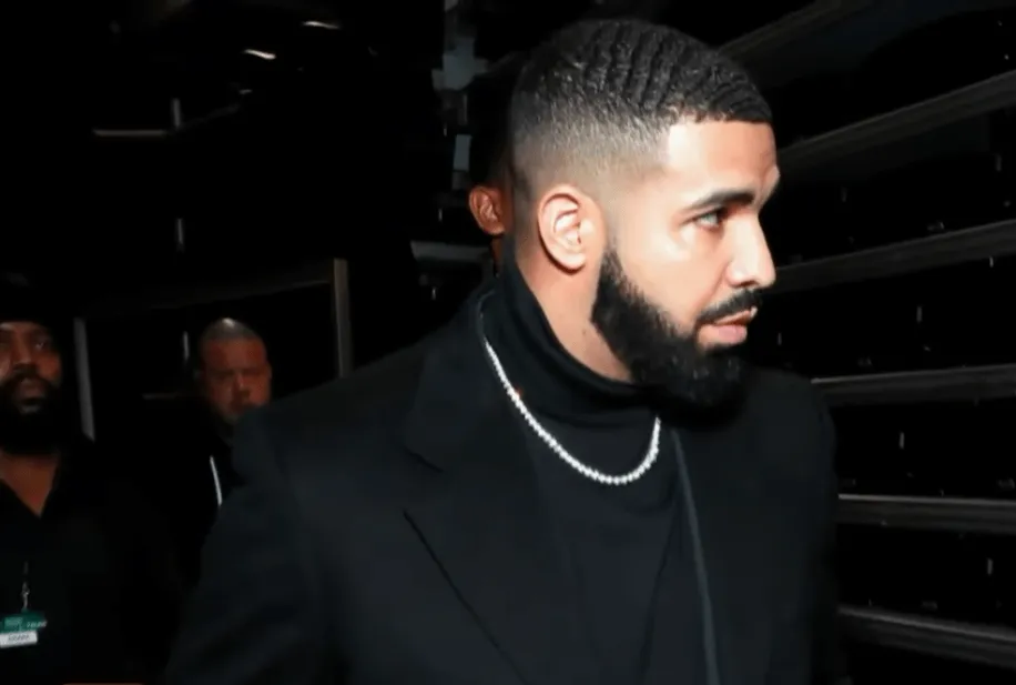 Drake wears a black turtleneck and a chain.