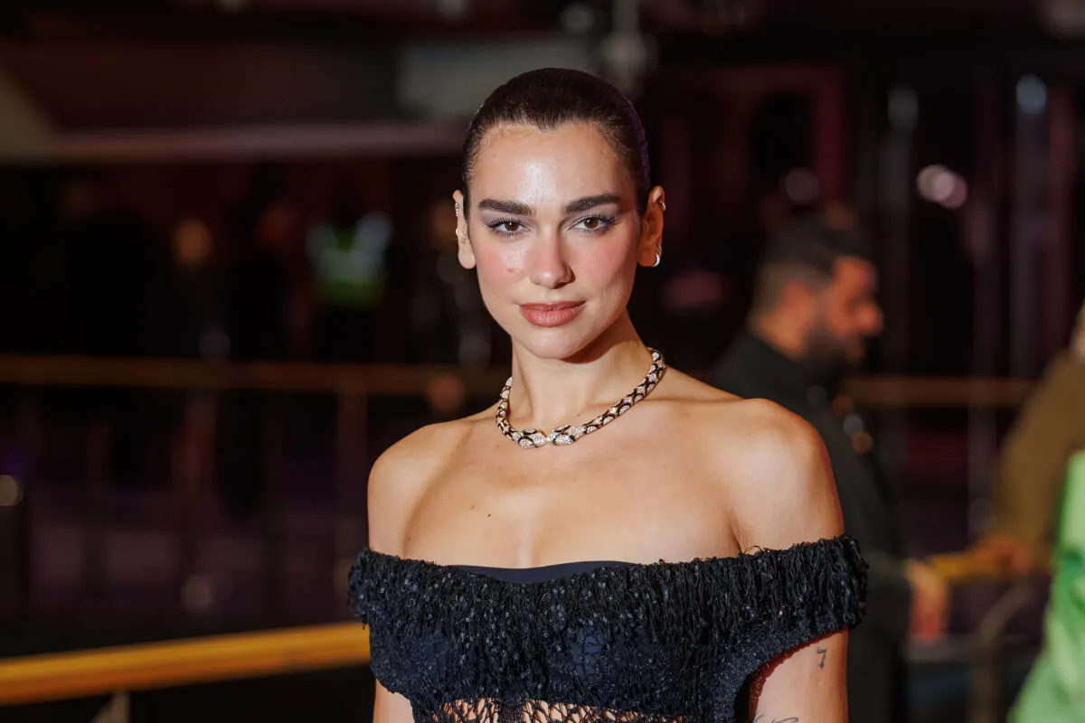 Dua Lipa wears a black strapless dress and a snake necklace.