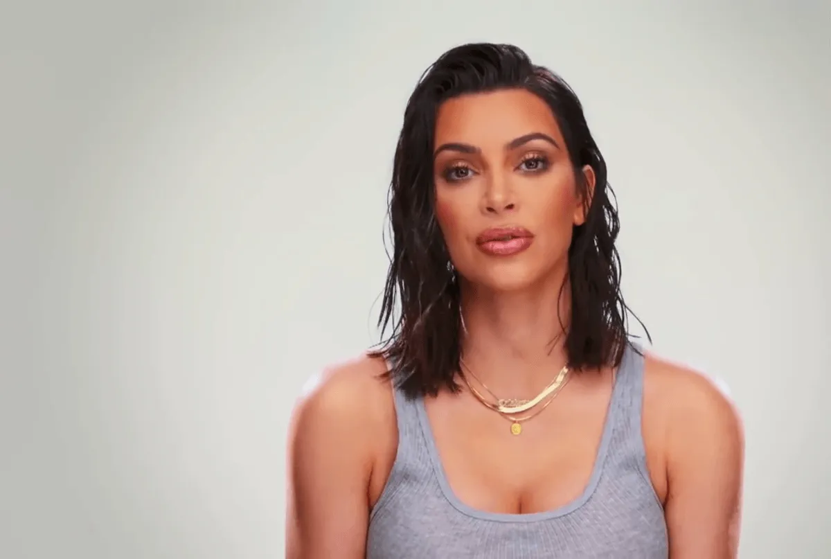 Kim Kardashian wears a gray tank top and a gold necklace.