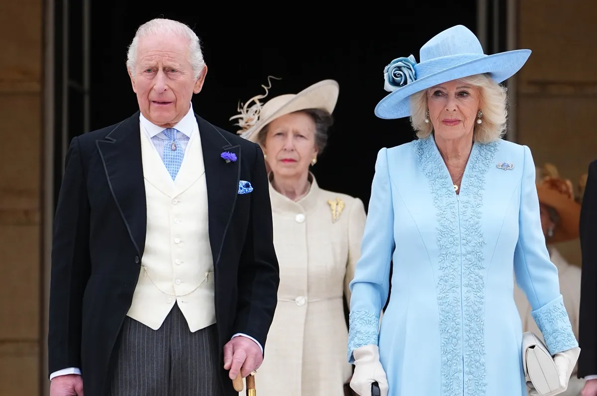 King Charles III, Princess Anne, and Queen Camilla stand at the top of the Garden steps before the start of a Royal Garden Party at Buckingham Palace