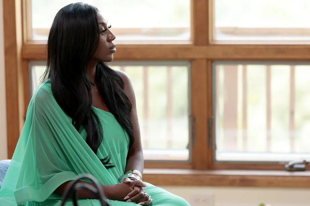 Wendy Osefo sitting in a green dress and looking out a window