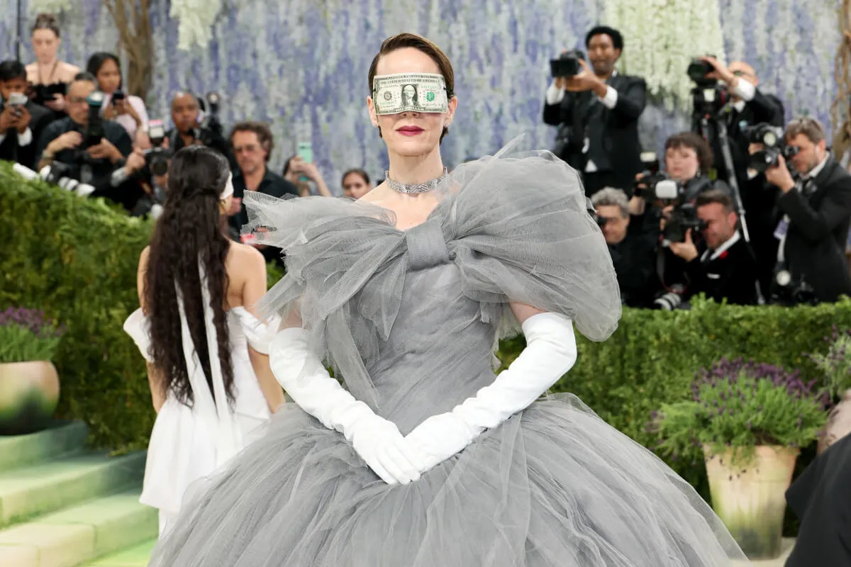 Sarah Paulson wears a gray dress with white gloves and a money mask at the Met Gala.