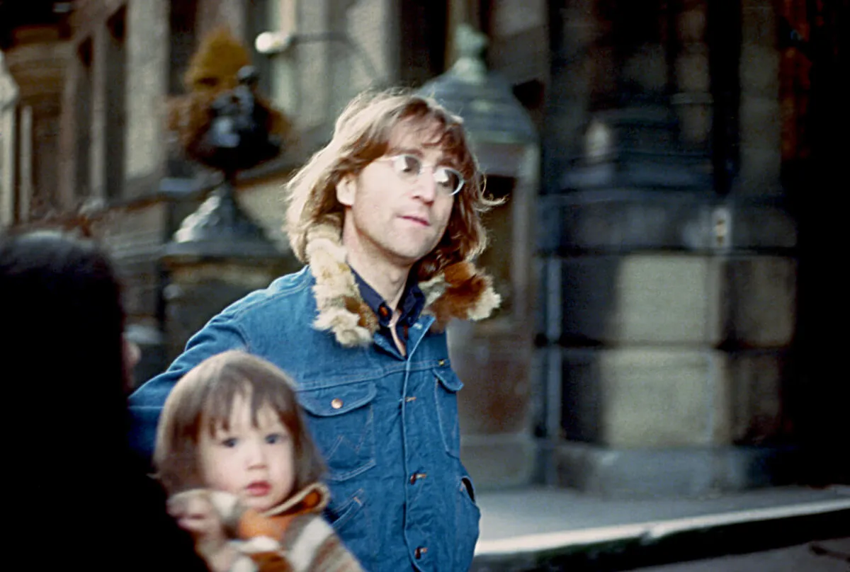 John Lennon wears a denim jacket and walks with his son, Sean.