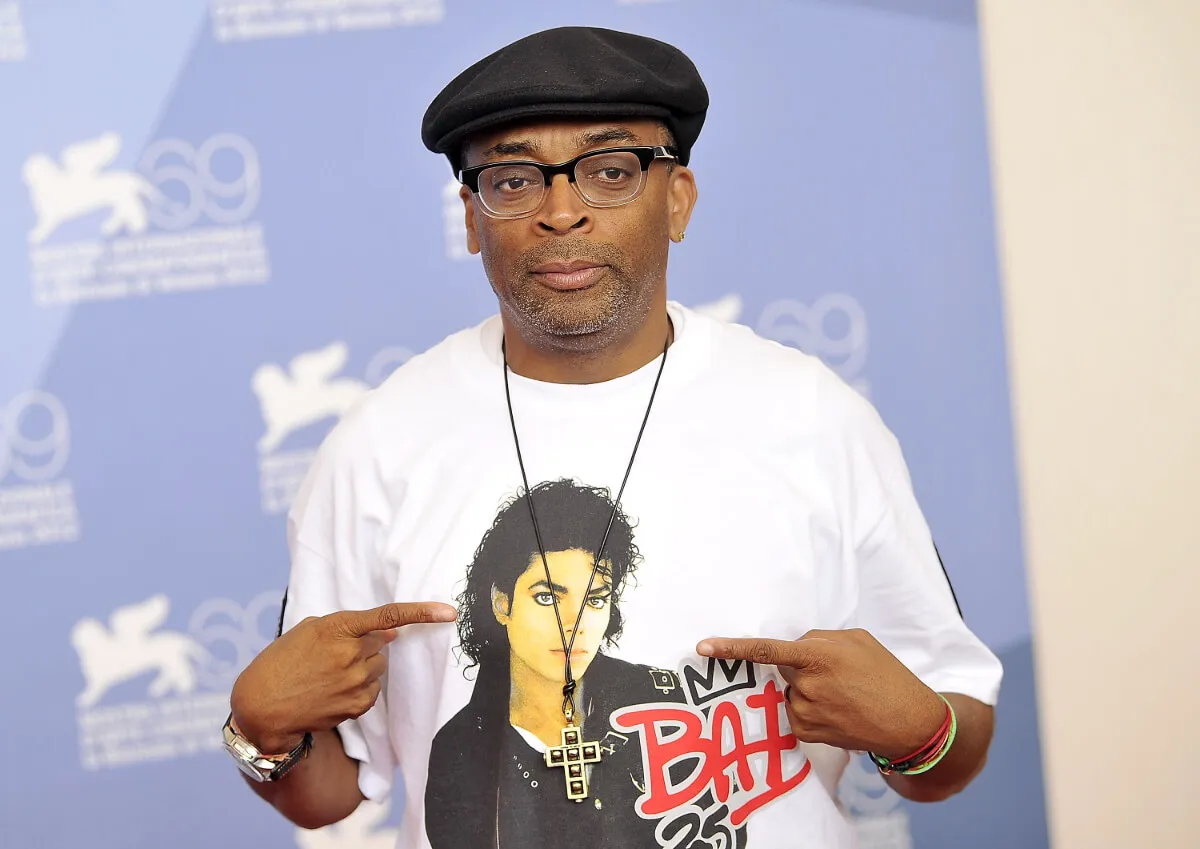 Spike Lee wears a hat and points to his shirt, which shows the cover of Michael Jackson's 'Bad.'