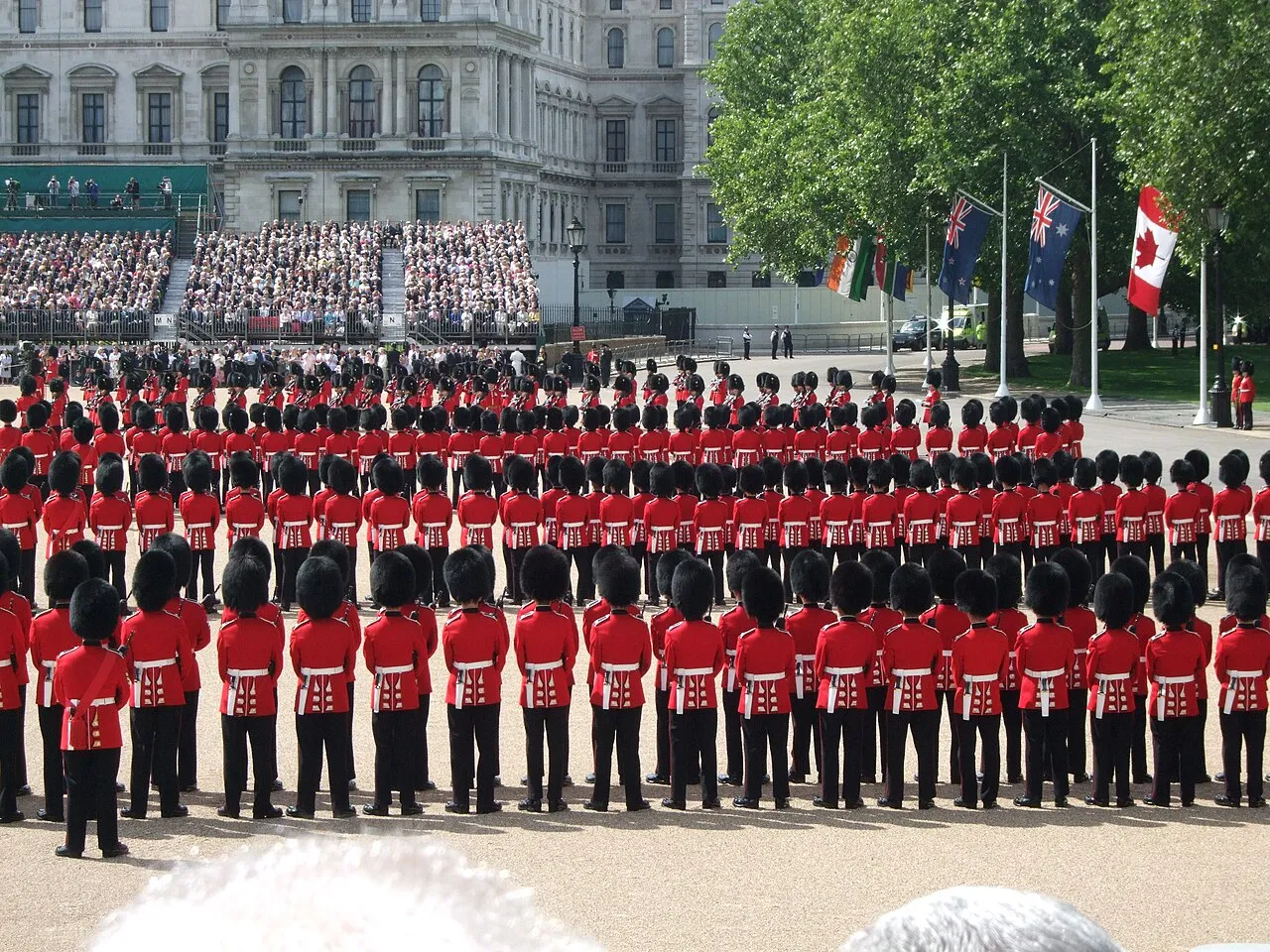 British troops in red jackets lined up for Trooping the Colour with grandstand in the background