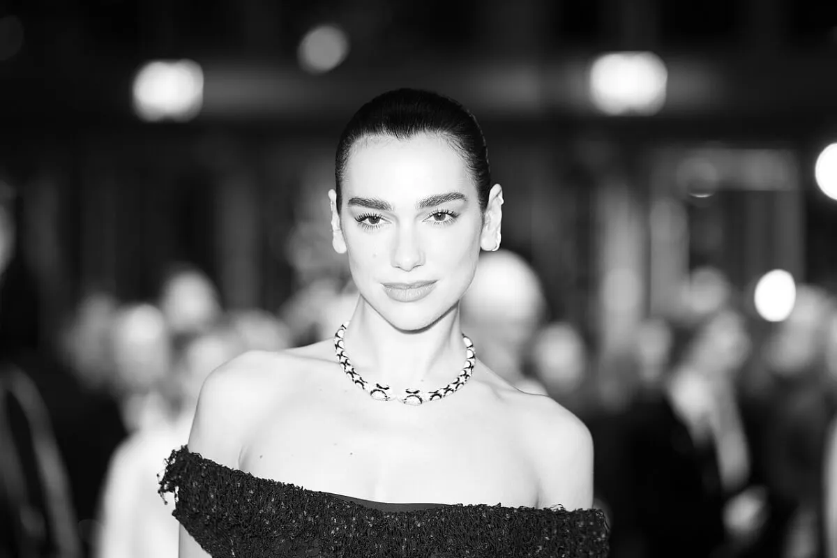 A black and white picture of Dua Lipa wearing an off-the-shoulder dress.