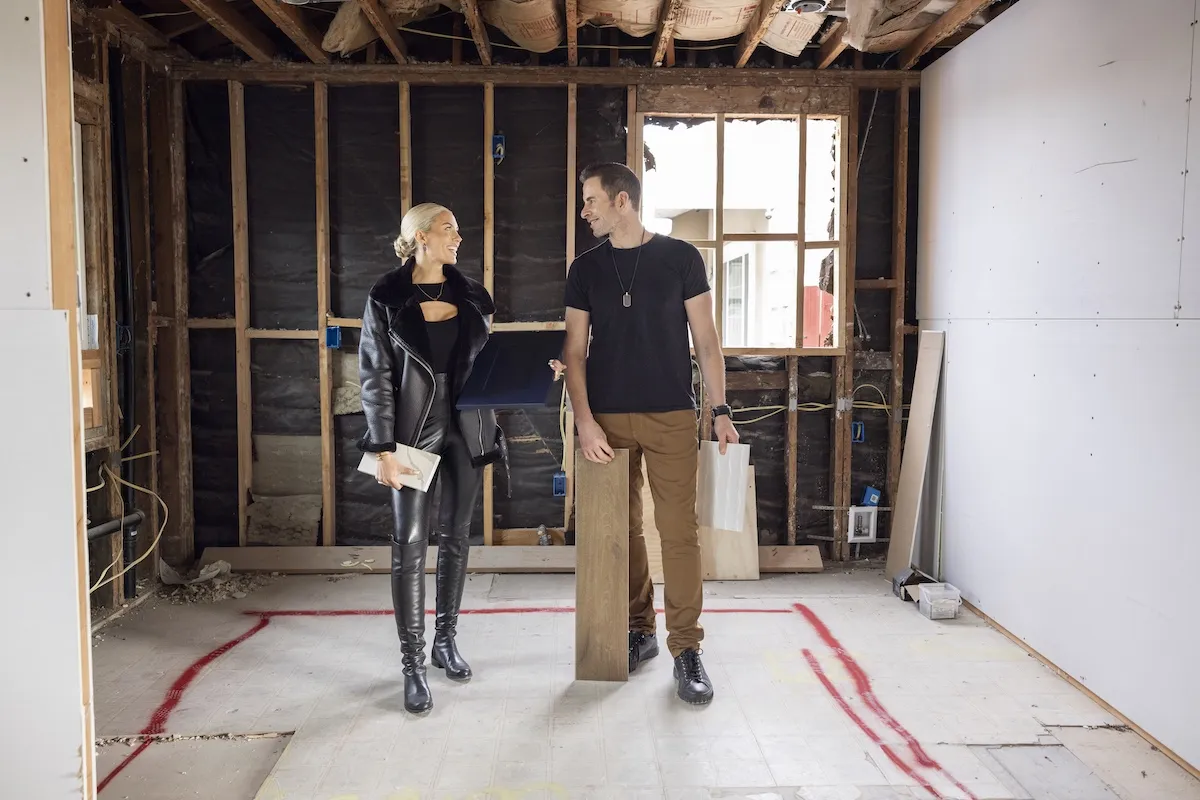Heather Rae El Moussa and Tarek El Moussa standing in an under-construction home in 'THe Flipping El Moussas'