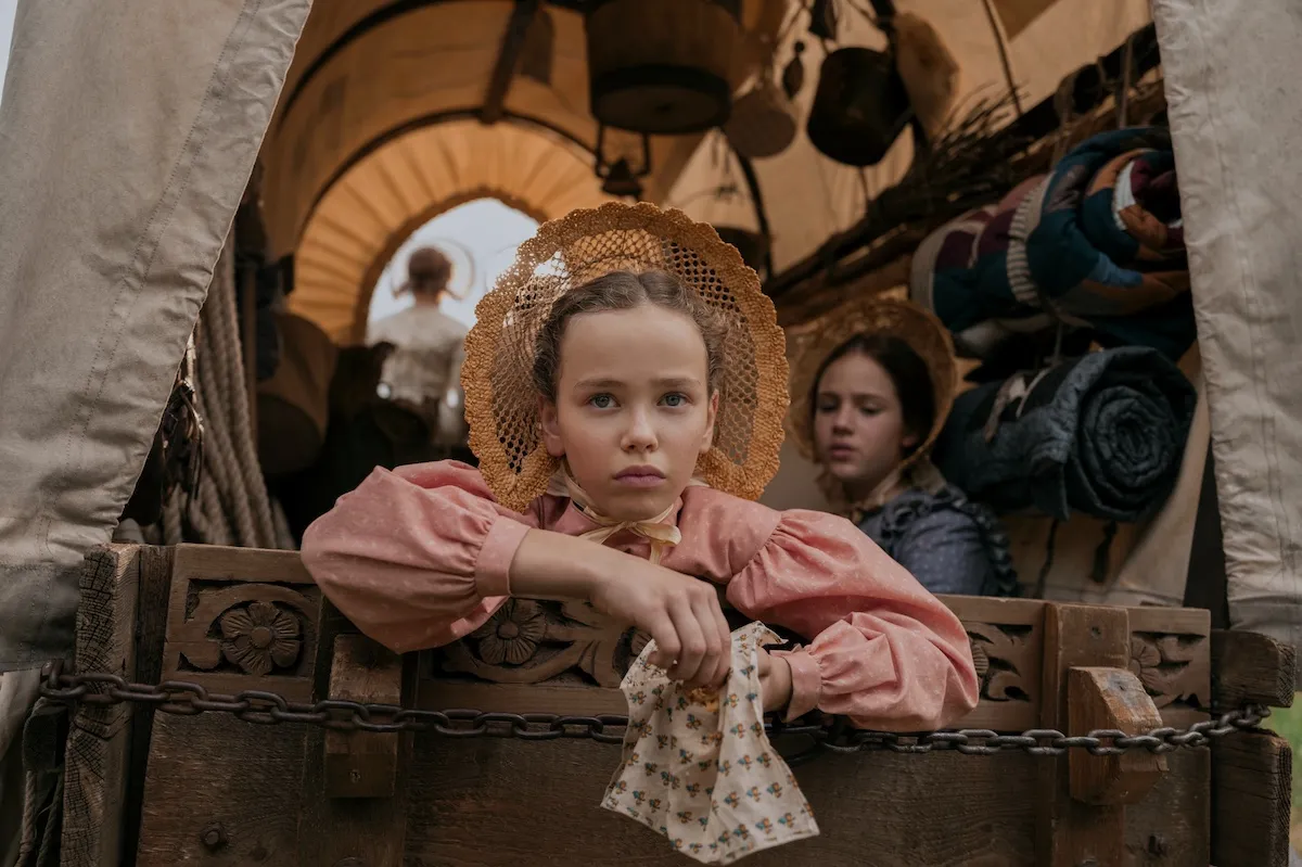 Laura looking out the back of a covered wagon in Netflix's 'Little House on the Prairie'