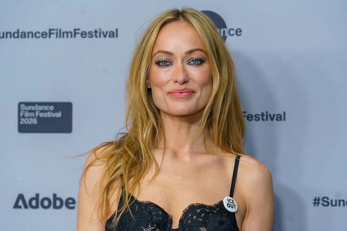Olivia Wilde wears a black dress with an ICE OUT pin.