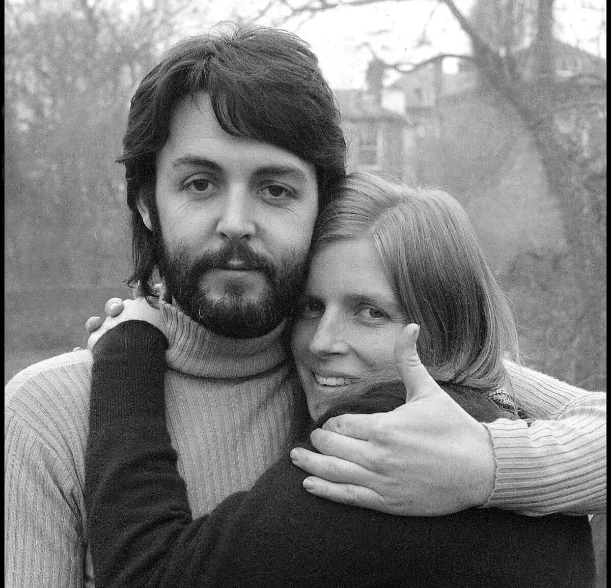 A black and white picture of Linda McCartney and Paul McCartney hugging.