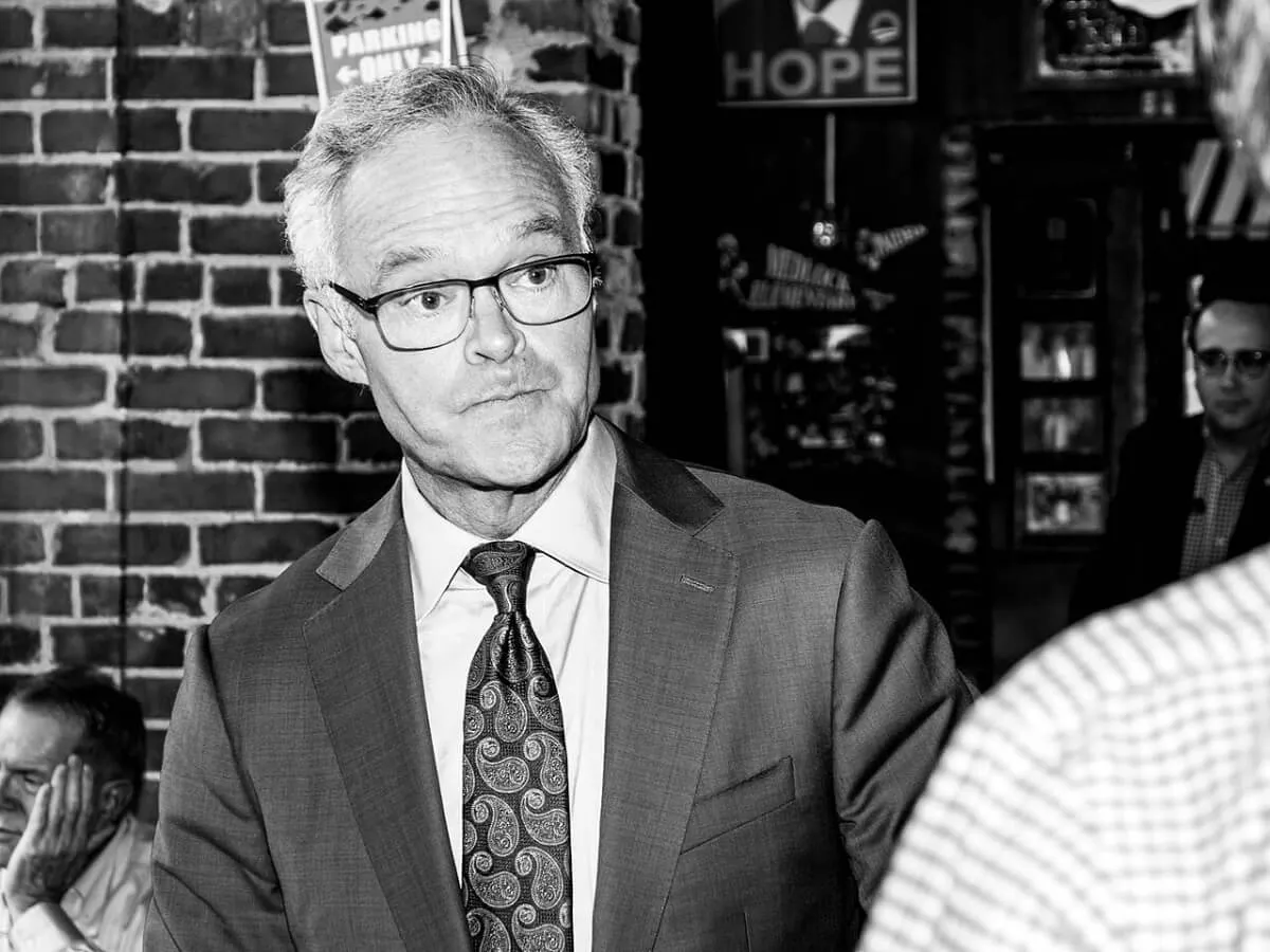 A black and white picture of Scott Pelley wearing a suit and glasses.
