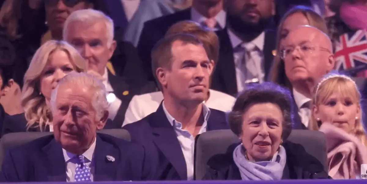 Screenshot of Peter Phillips sitting at concert behind his uncle King Charles, and his mother, Princess Anne