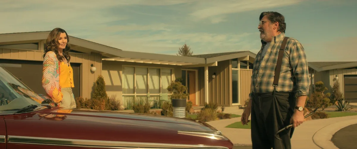 Geena Davis and Alfred Molina standing by a vintage car in 'The Boroughs' on Netflix