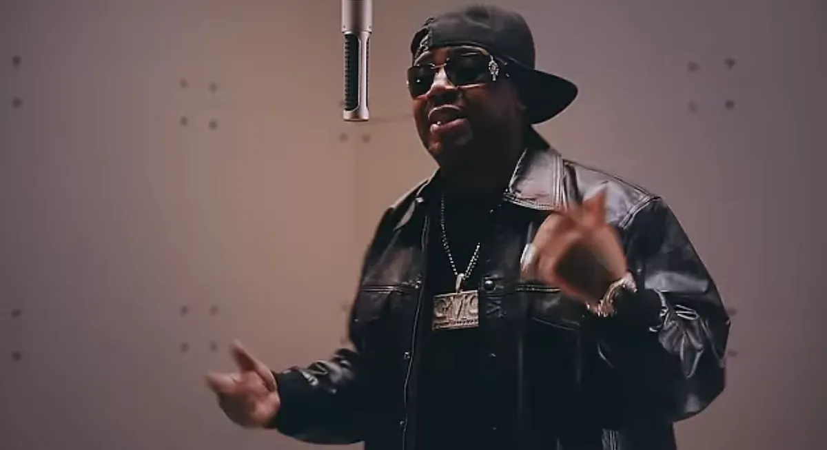 Twista standing in front of a microphone and wearing sunglasses