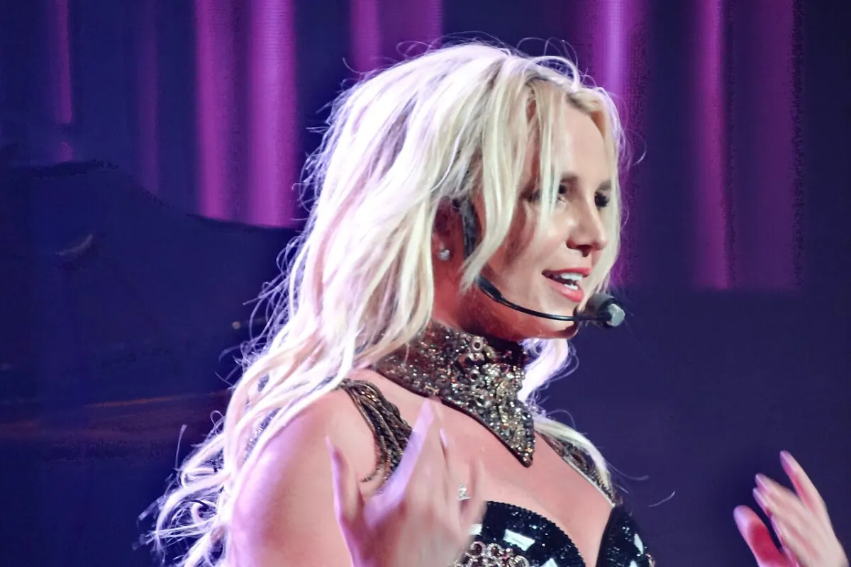 Britney Spears wears a sparkly bandana around her neck and has a headset microphone.
