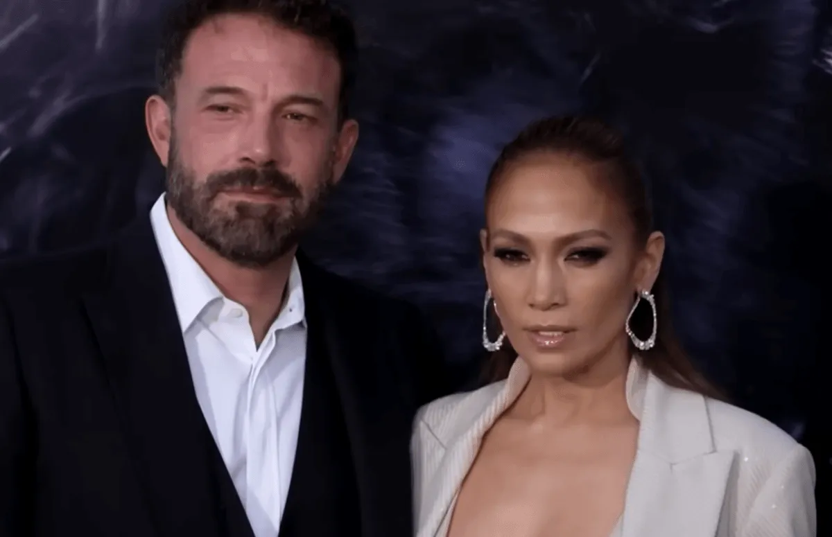 Ben Affleck wears a suit and stands with Jennifer Lopez.