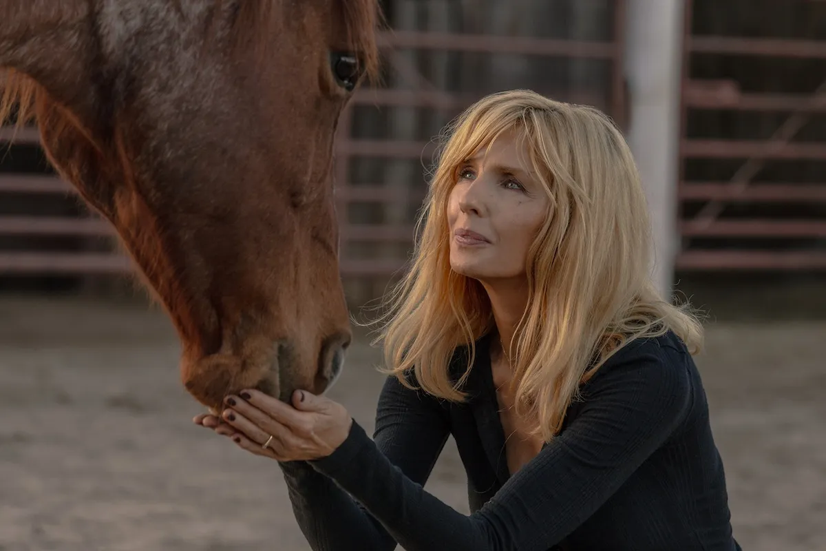 Beth Dutton (Kelly Reilly) crouched in front of a horse in 'Dutton Ranch'