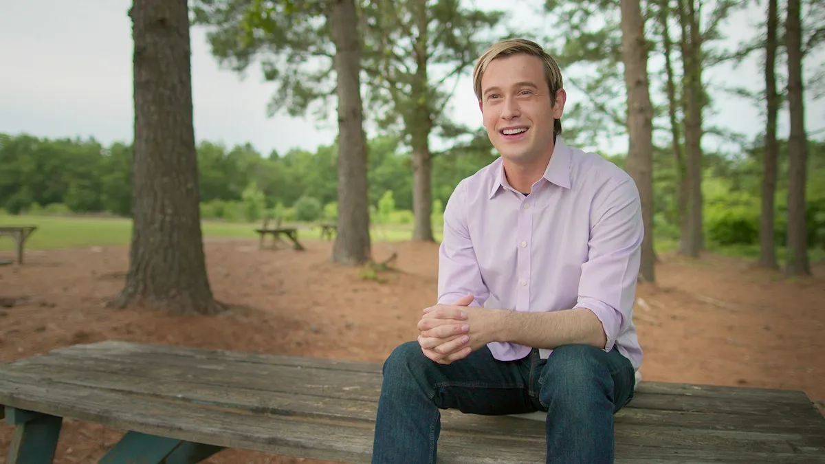 Tyler Henry sitting on a picnic table in the woods