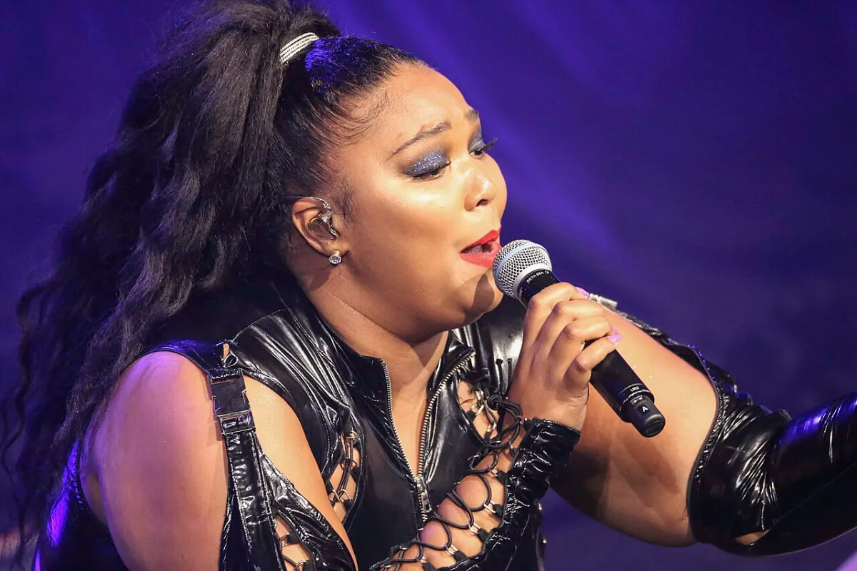 Lizzo wears black and sings into a microphone.