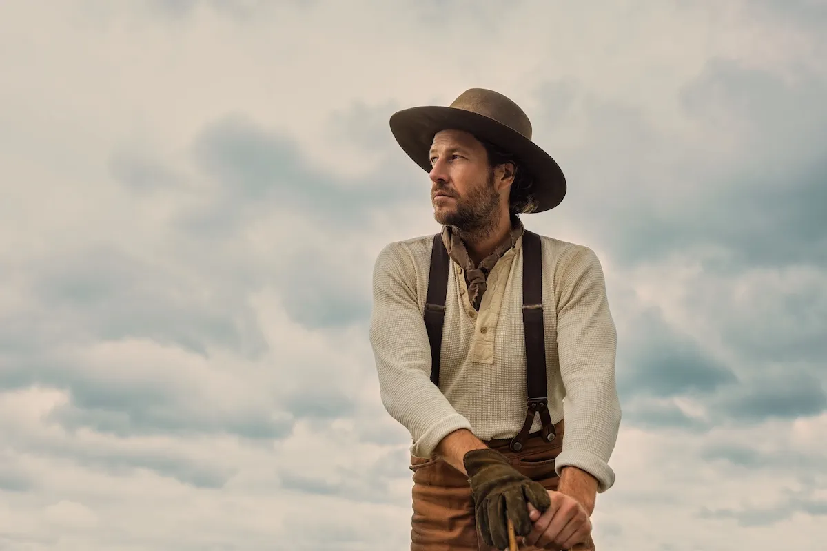 Luke Bracey as Charles 'Pa' Ingalls against a sky with clouds in Netflix's 'Little House on the Prairie'