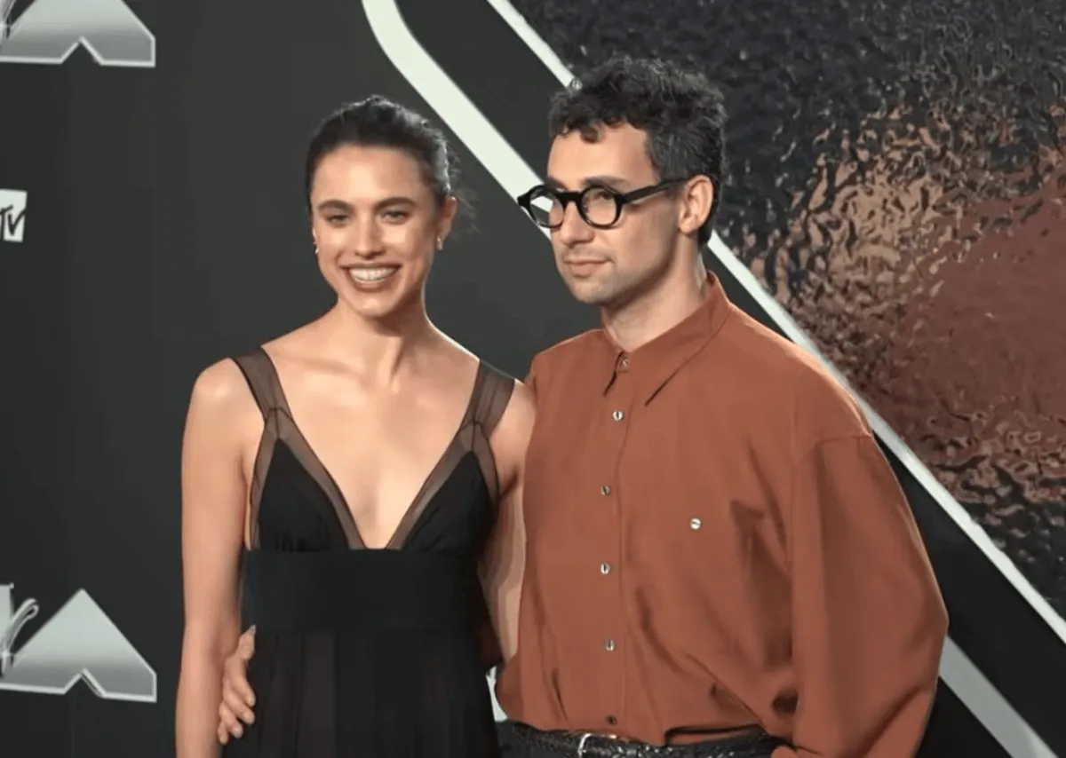 Margaret Qualley wears a black dress and stands with Jack Antonoff, who wears brown.