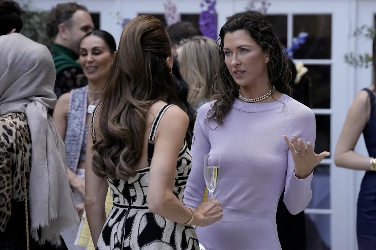 Margo Stilley in a lavender dress talking to someone in 'Ladies of London' on Bravo