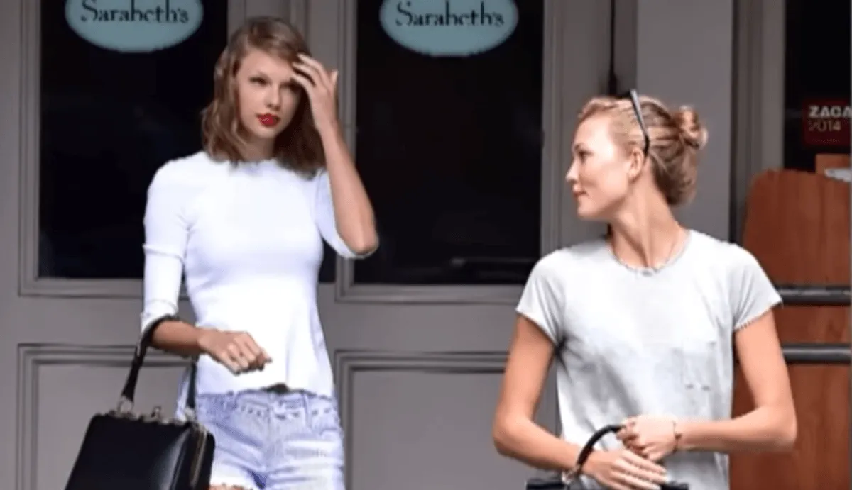 Taylor Swift and Karlie Kloss wear white shirts and walk on steps together.